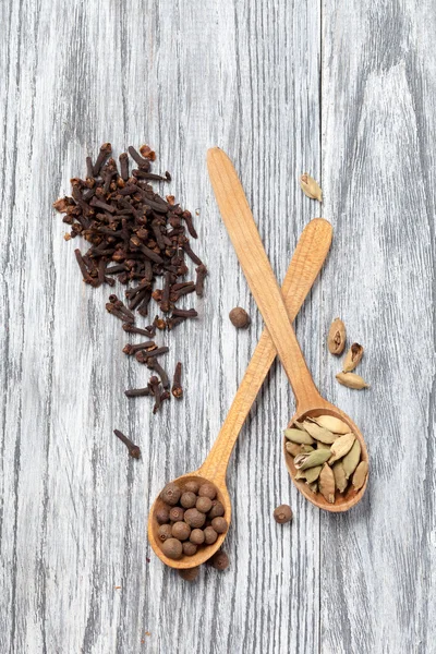 Nutmeg, clove and allspice in old spoon on wooden table — Stock Photo, Image