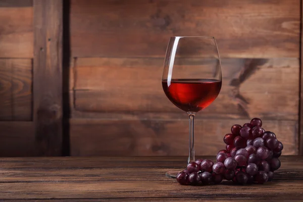 Vinho tinto em vidro com uva em madeira — Fotografia de Stock