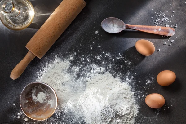 Harina e ingridientes sobre mesa negra — Foto de Stock