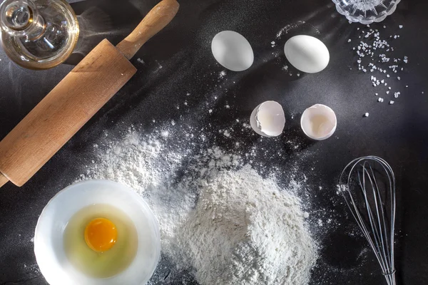 Mjöl och ingrediens på svart bord — Stockfoto