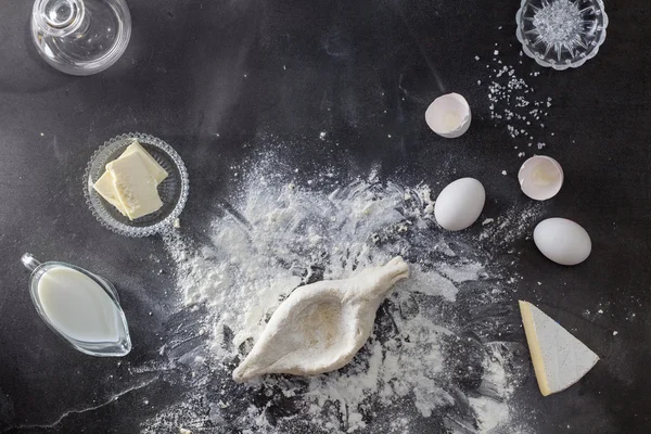 Masa sobre mesa negra con harina e ingridientes — Foto de Stock