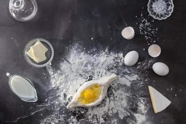 Těsto na černý stůl s moukou a ingredience — Stock fotografie