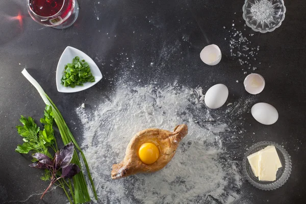 Khachapuri op zwarte tafel met bloem — Stockfoto