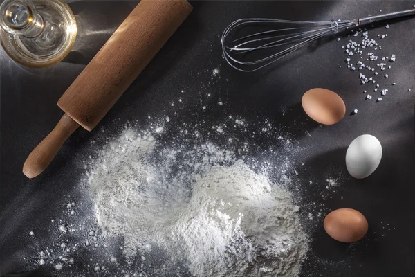 Mjöl och ingredienser på svart bord — Stockfoto