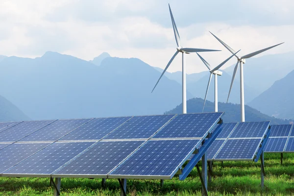 Солнечные батареи и ветряные турбины против гор — стоковое фото