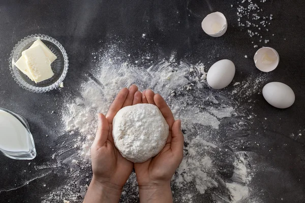 Woman's hands knead dough on table with flour — Stock Photo, Image