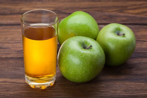 Szklanka soku jabłkowego i jabłka na drewno — Zdjęcie stockowe