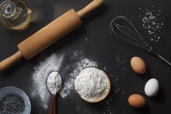 Mjöl och ingredienser på svart bord — Stockfoto