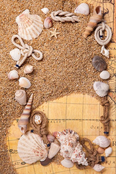Рамка из различных раковин на песке и старой карте — стоковое фото