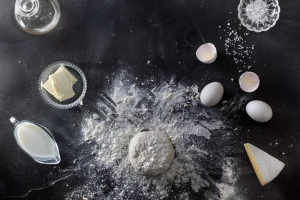 Masa sobre mesa negra con harina e ingredientes —  Fotos de Stock