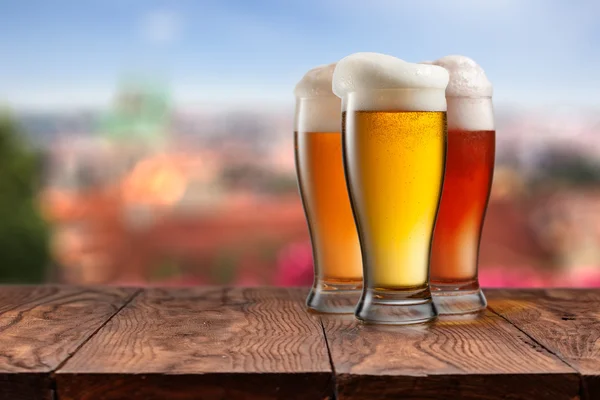 Bicchieri di birra diversa su tavolo di legno contro Praga — Foto Stock