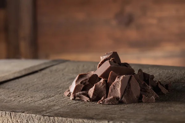 Stukken van melkchocolade op hout — Stockfoto