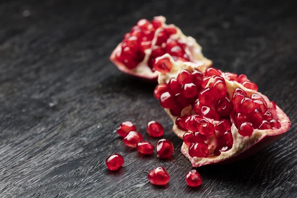 Pomegranate on black wood — Stock Photo, Image