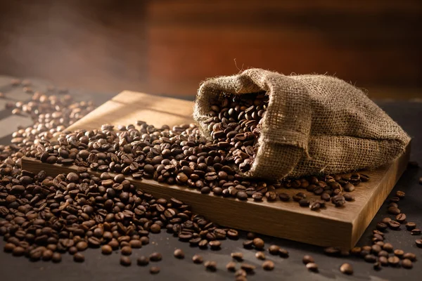 Rozlany ziarna kawy w torbie na drewno — Zdjęcie stockowe
