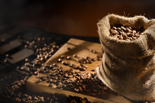 spilled coffee beans in bag on wood