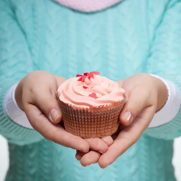 Frau hält rosa Cupcake auf weiß — Stockfoto