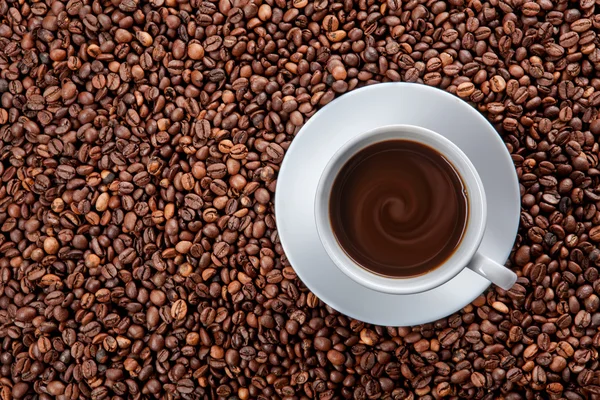 Taza blanca de café negro en granos — Foto de Stock