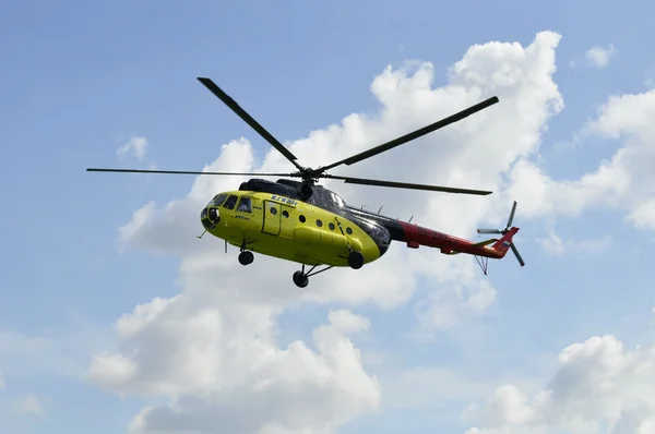 A sárga mi-8 helikopter repül ellen felhők. — Stock Fotó