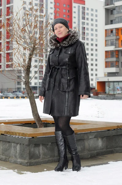 La mujer en el abrigo de piel de oveja cuesta contra los nuevos edificios —  Fotos de Stock