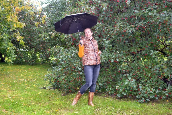 La femme avec un parapluie et en bottes de gomme coûte dans le parc d'automne — Photo