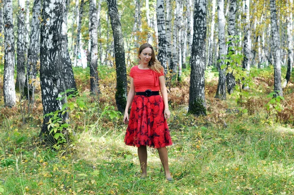 La belle femme en vêtements rouges dans le bois d'automne . — Photo