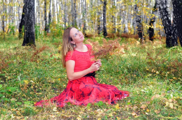 La belle femme en vêtements rouges dans le bois d'automne — Photo
