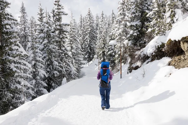 Mãe andando na neve com o bebê de costas — Fotografia de Stock