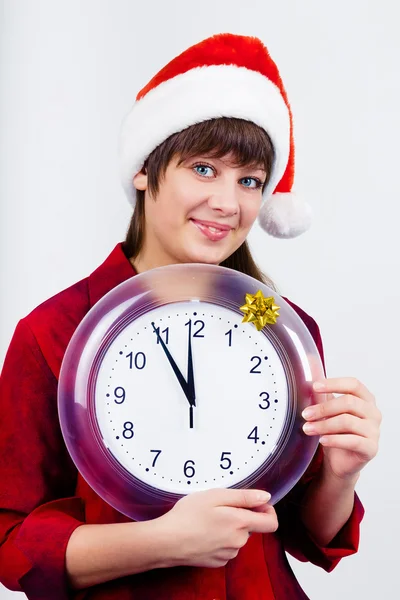 Belle fille aux yeux bleus en chapeau de Père Noël avec horloge — Photo