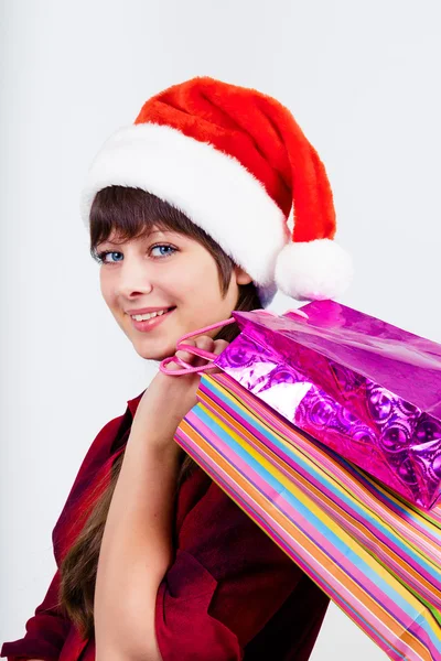 Blauäugiges schönes Mädchen mit Weihnachtsmann-Hut und Geschenken — Stockfoto