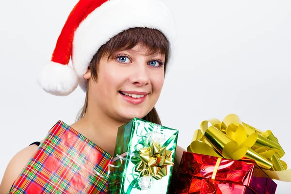 Blauäugiges schönes Mädchen mit Weihnachtsmann-Hut und Geschenken — Stockfoto