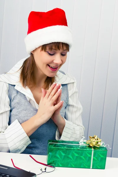 Dívka v kanceláři v Santa klobouky s dárkem — Stock fotografie