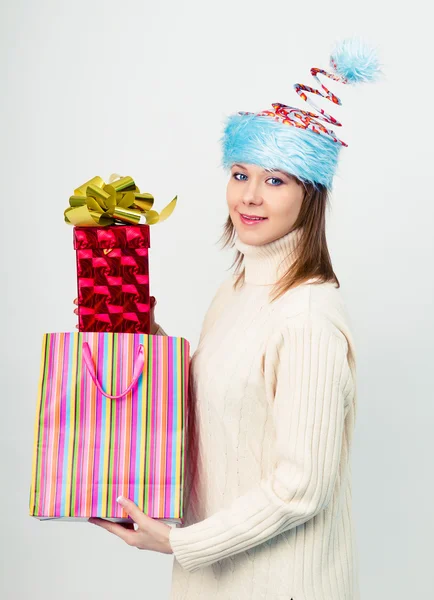 Happy girl in an unusual Christmas hat with gift boxes — Stock Photo, Image