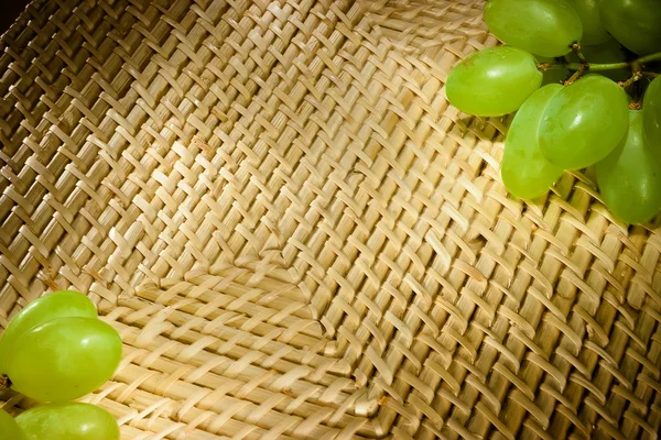 Wicker texture with green grapes on the corners — Stock Photo, Image