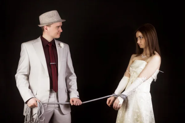 Photo studio. Groom snared rope bride. fun — Stock Photo, Image