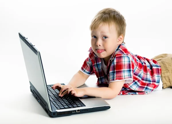 Niño acostado en el suelo con un ordenador portátil — Foto de Stock