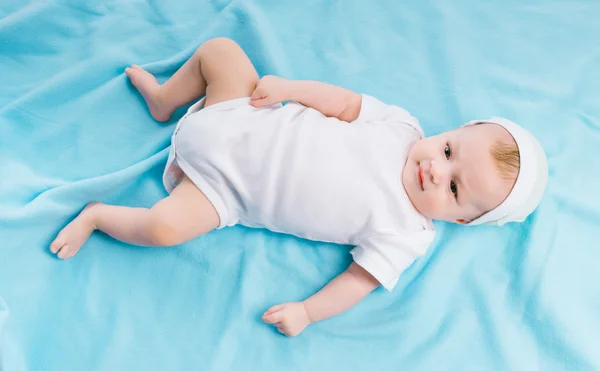 Bambino in cappello sdraiato su una coperta blu — Foto Stock