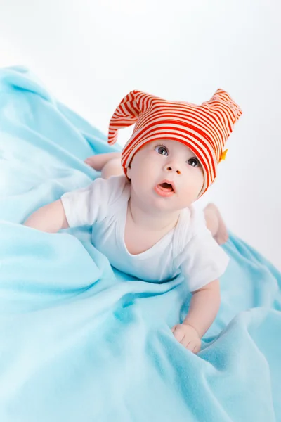 Toddler in a striped hat on a blue blanket — Zdjęcie stockowe