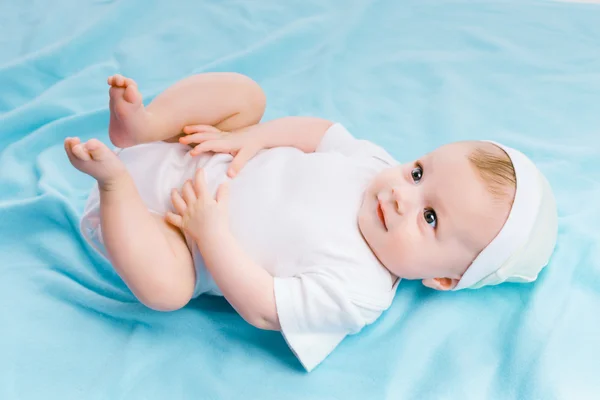 Bambino in cappello sdraiato su una coperta blu — Foto Stock