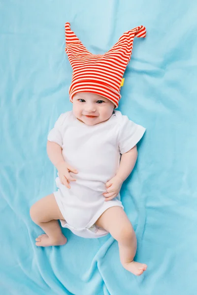 Toddler in a striped hat on a blue blanket — Stockfoto