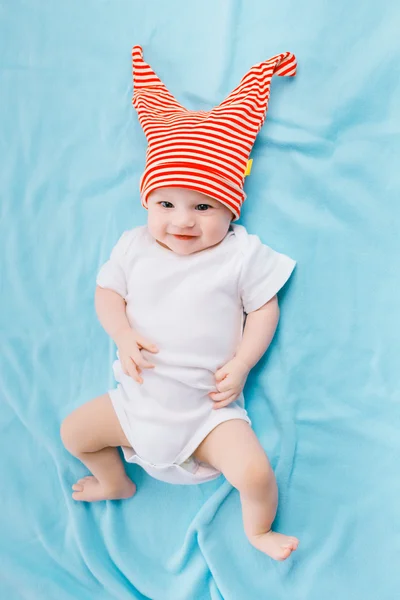 Niño pequeño con un sombrero a rayas en una manta azul — Foto de Stock