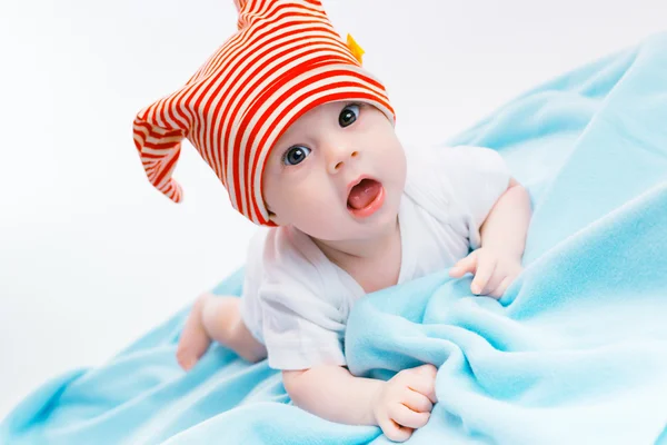 Toddler in a striped hat on a blue blanket — Stok fotoğraf