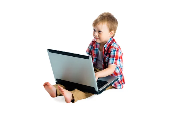 Beyaz zemin üzerinde bir dizüstü bilgisayar ile ekose gömlekli çocuk. — Stok fotoğraf