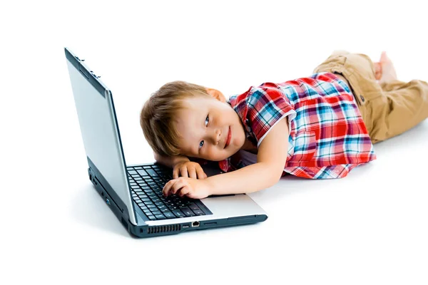 Niño en una camisa a cuadros con un ordenador portátil sobre un fondo blanco . — Foto de Stock