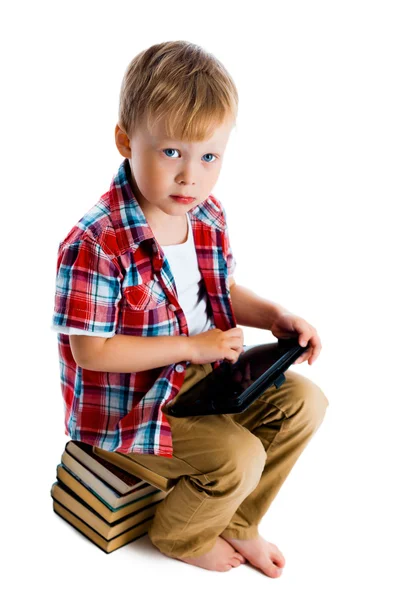 Liten pojke med en Tablet PC: n sitter på böcker — Stockfoto