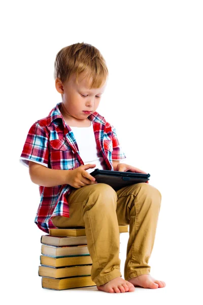 Menino com um Tablet PC sentado sobre os livros — Fotografia de Stock