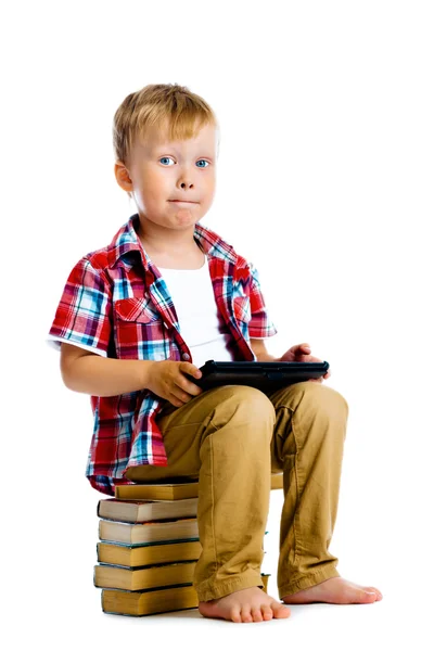 Chico con un Tablet PC sentado en los libros — Foto de Stock