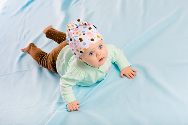 Blue-eyed baby in hat crawling — Stock Photo, Image