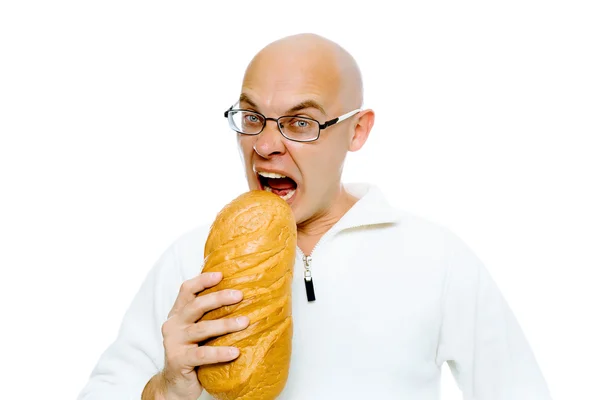 Homem careca faminto morde um grande pão. Estúdio. isolado — Fotografia de Stock