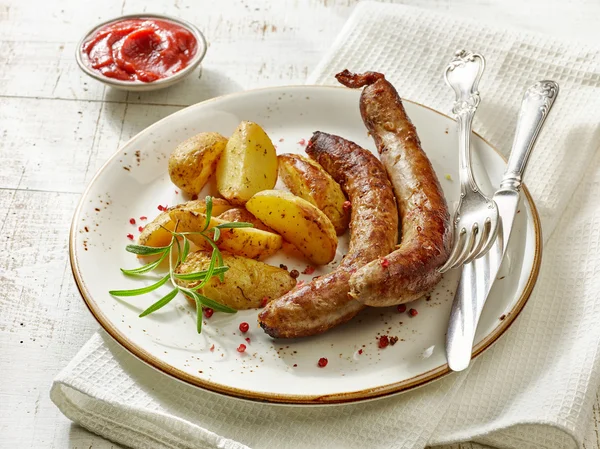 Gegrilde worstjes en aardappelen op witte houten tafel — Stockfoto