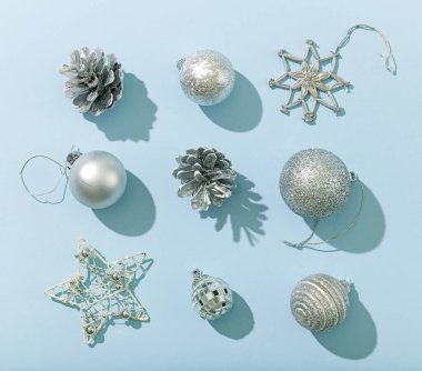 mavi kağıt zemin üzerinde çeşitli gümüş rengi Noel süslemeleri, düz döşeme, üst görünüm